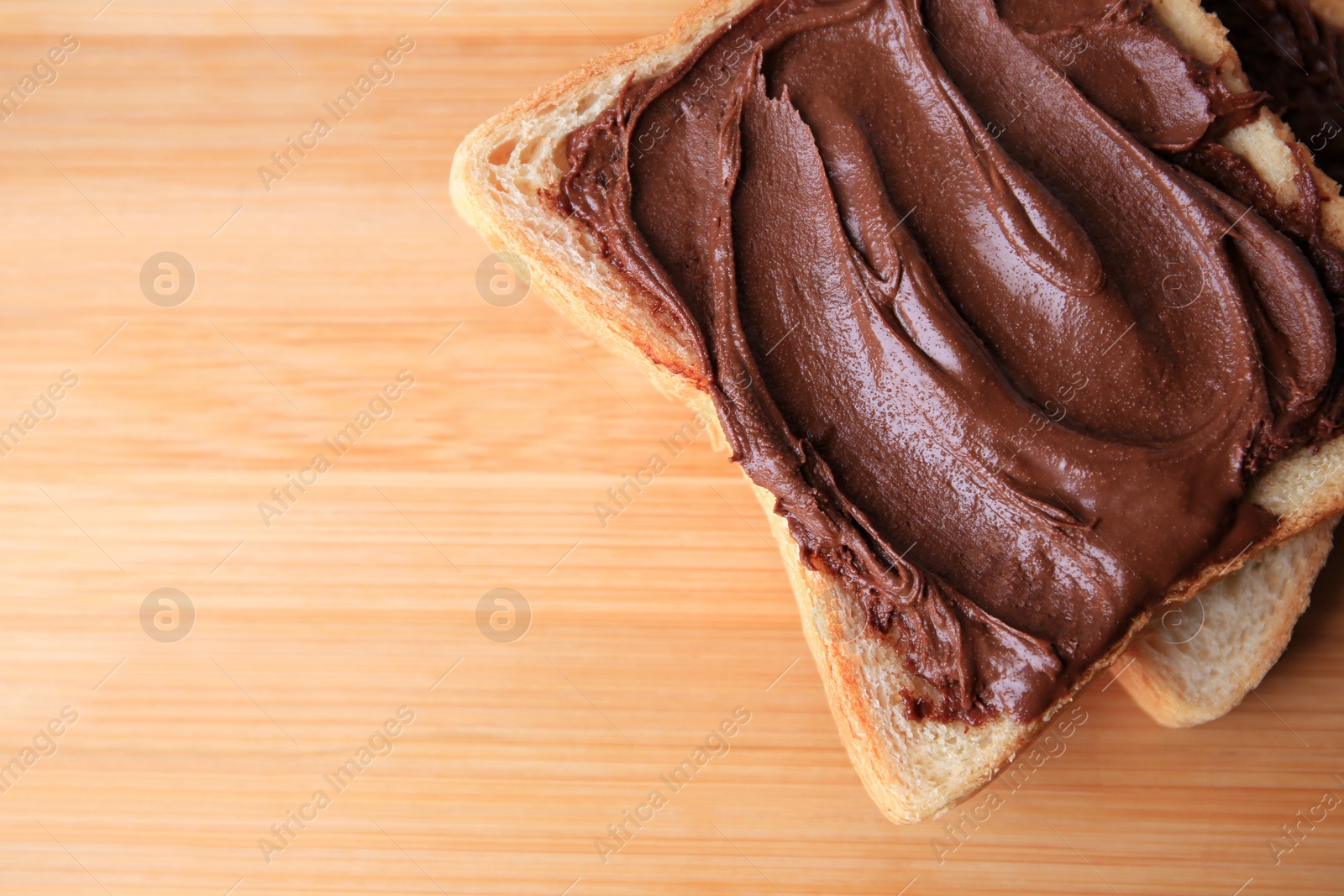 Photo of Tasty toast with chocolate paste on wooden table, top view. Space for text