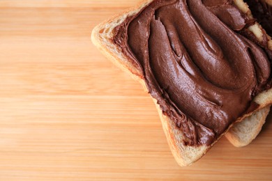 Photo of Tasty toast with chocolate paste on wooden table, top view. Space for text