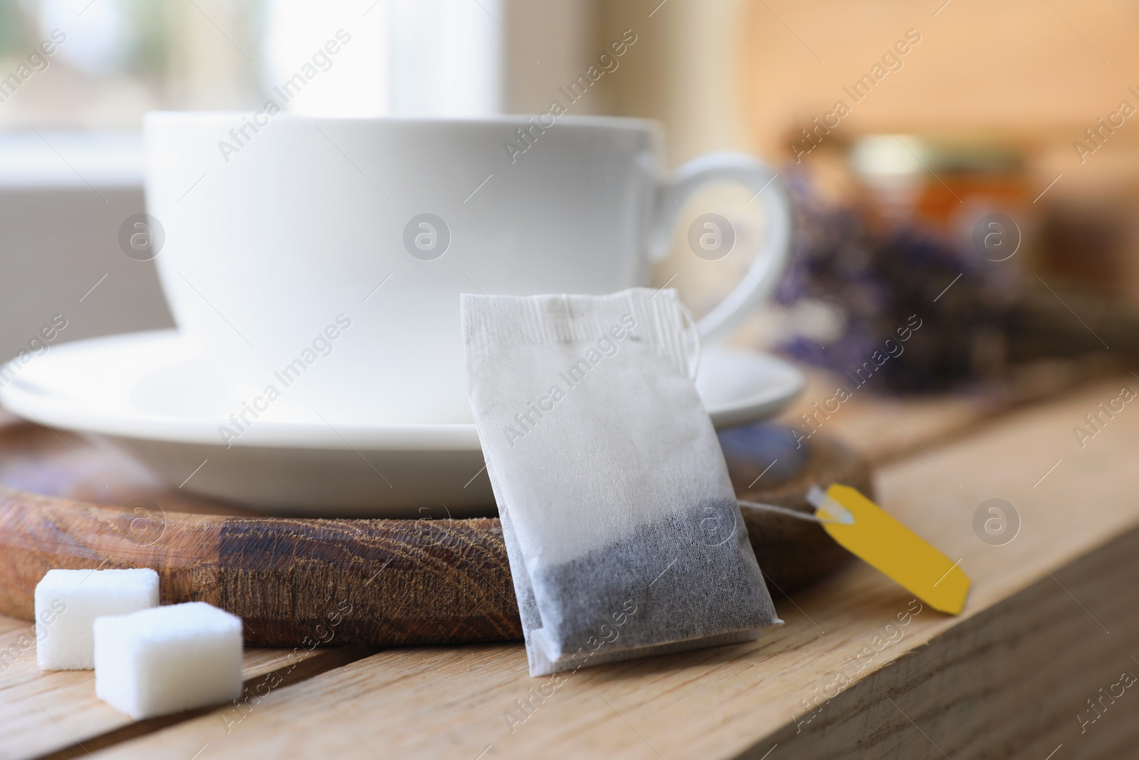 Photo of Tea bag and cup on wooden table indoors, closeup