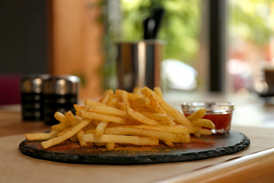 Photo of Delicious hot french fries with red sauce served on table