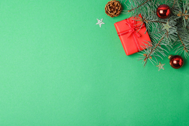 Flat lay composition with decorated fir branch and gift on green background, space for text. Winter holidays