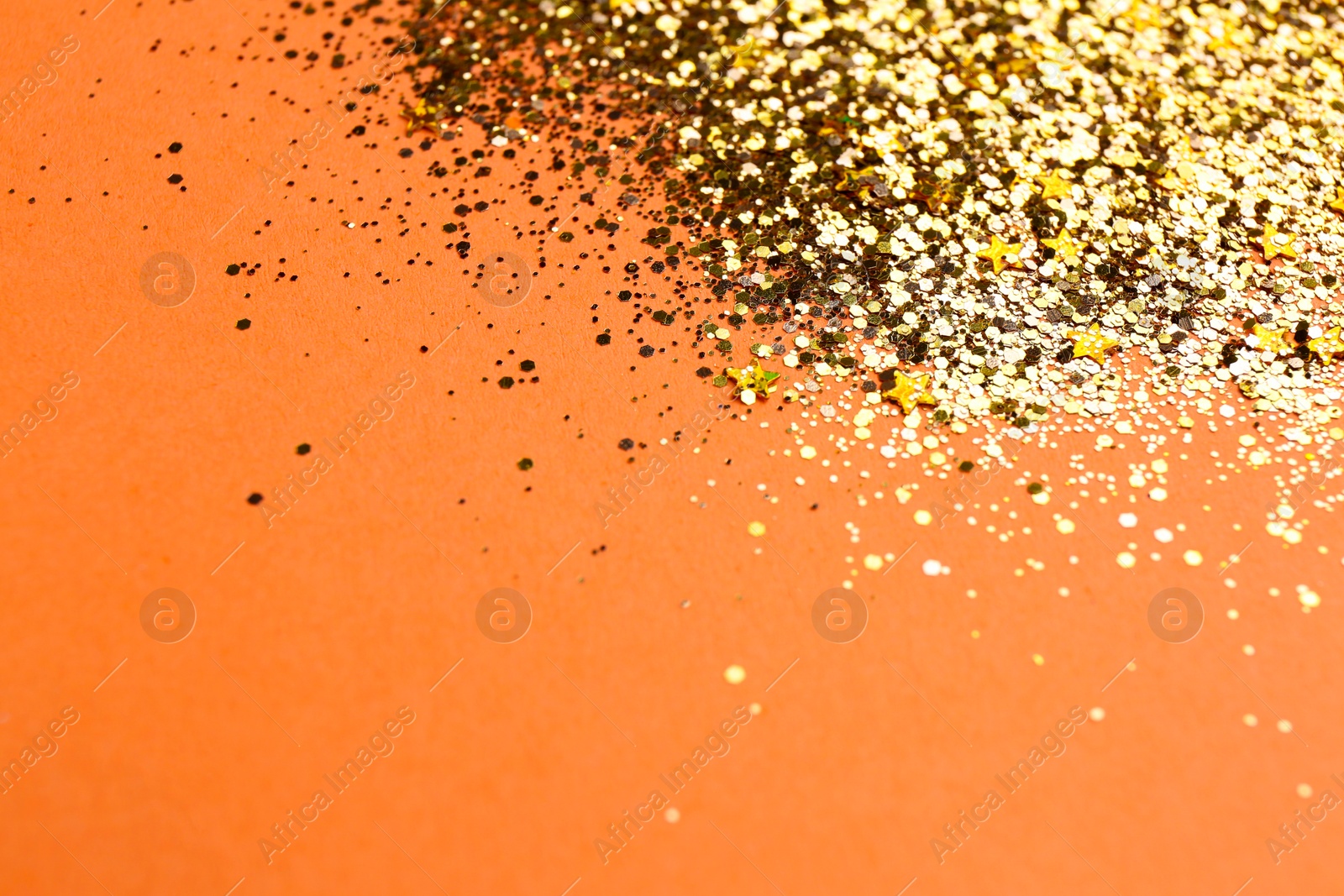 Photo of Shiny bright golden glitter on pale coral background, closeup. Space for text