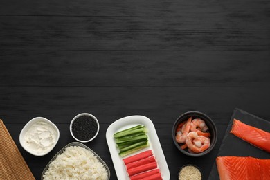 Photo of Making sushi rolls. Flat lay composition with ingredients on black wooden table. Space for text