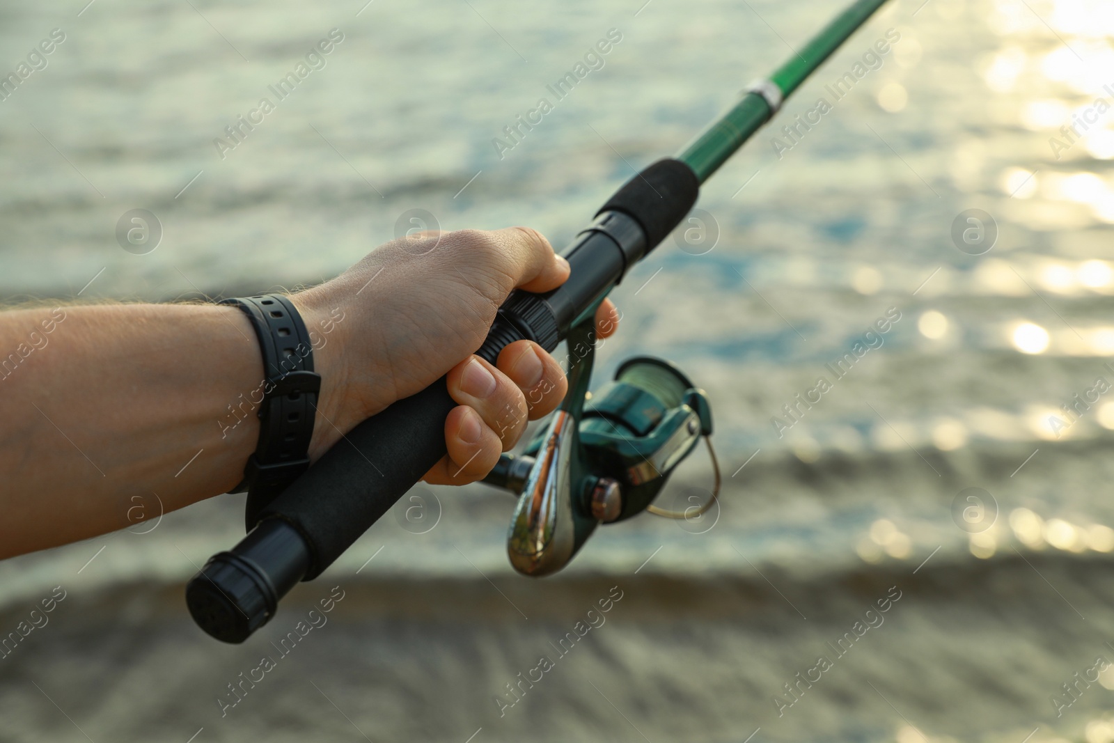Photo of Fisherman with rod fishing at riverside, closeup. Space for text