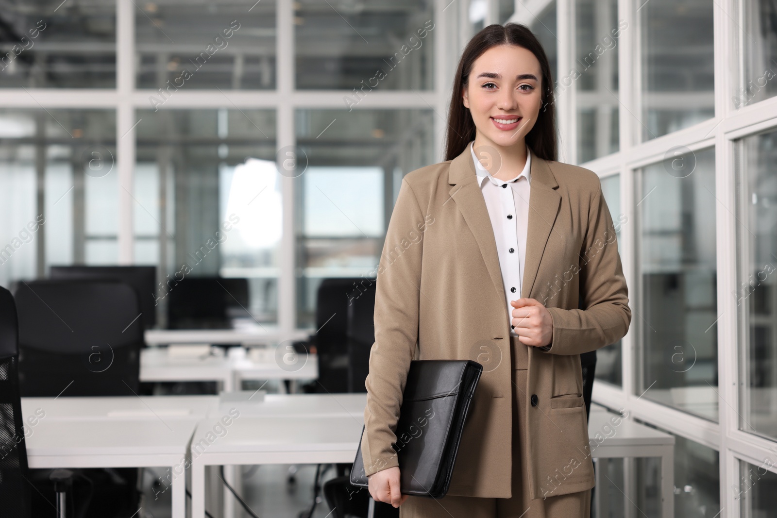 Photo of Happy real estate agent with leather portfolio indoors. Space for text