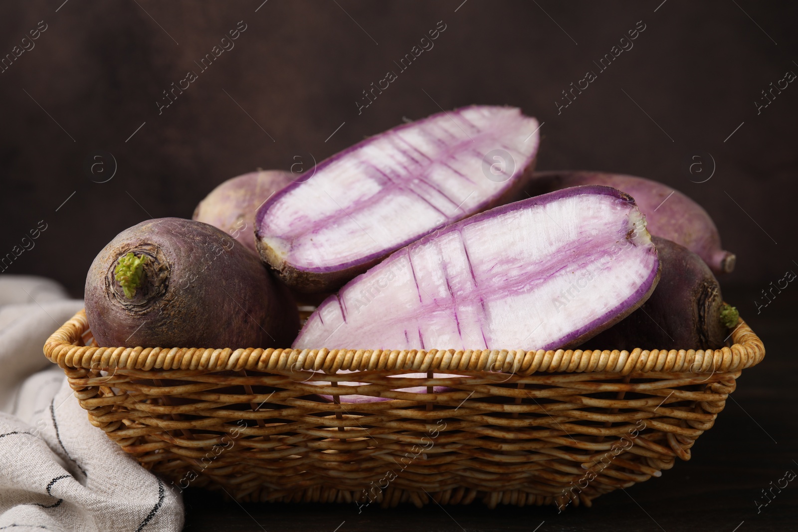 Photo of Purple daikon radishes in wicker basket on wooden table