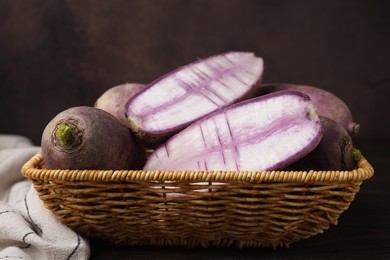 Photo of Purple daikon radishes in wicker basket on wooden table