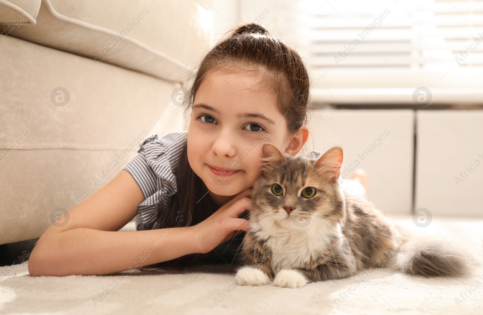 Photo of Cute little girl with cat lying on carpet at home. First pet
