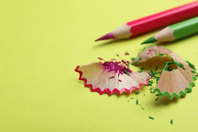 Photo of Pencils and shavings on light green background, closeup. Space for text