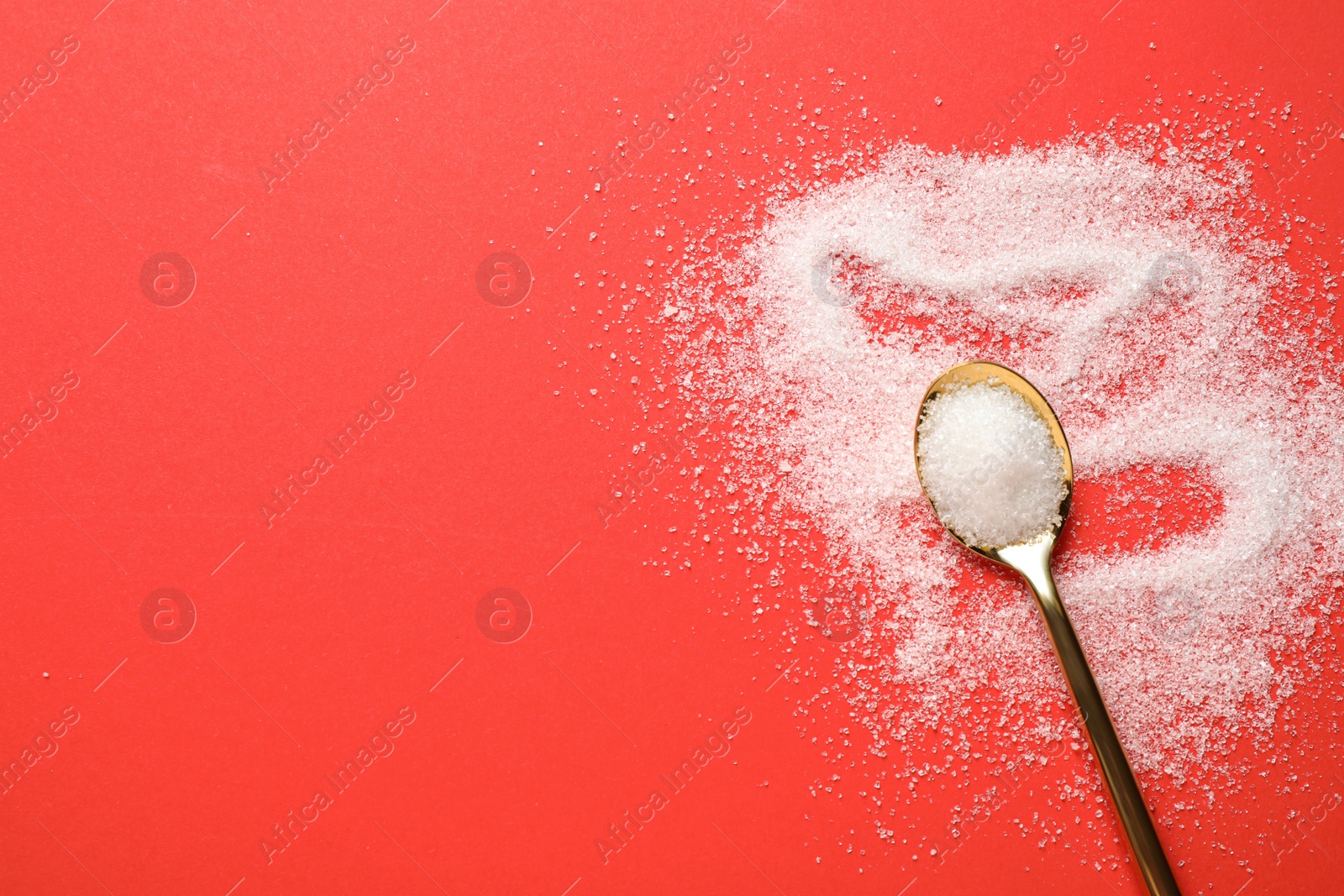 Photo of Granulated sugar and spoon on red background, flat lay. Space for text