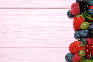 Photo of Mix of different fresh berries and mint on pink wooden table, flat lay. Space for text