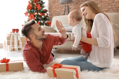 Photo of Happy couple with baby celebrating Christmas together at home