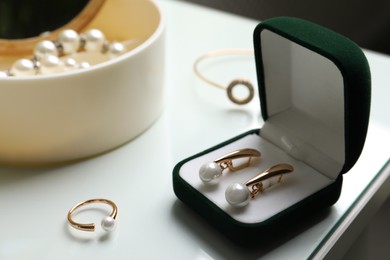 Elegant golden earrings in box on white table, closeup view