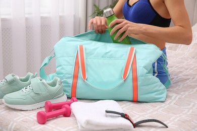 Woman packing sports stuff for training into bag at home, closeup