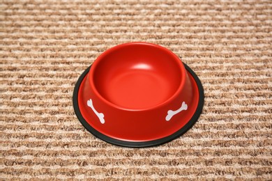 Photo of Empty red feeding bowl on soft carpet