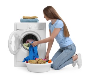 Photo of Beautiful young woman taking laundry out of washing machine on white background