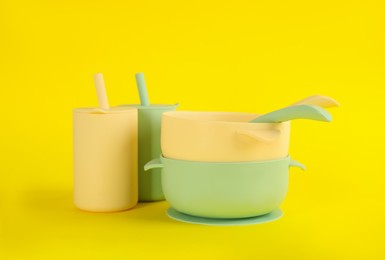 Set of plastic dishware on yellow background. Serving baby food