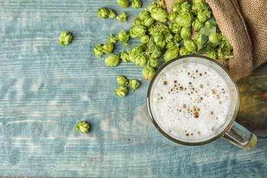 Photo of Flat lay composition with tasty beer, fresh green hops and space for text on wooden background