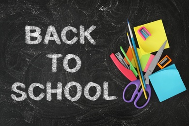 Image of Text Back To School and different stationery on black chalkboard, flat lay