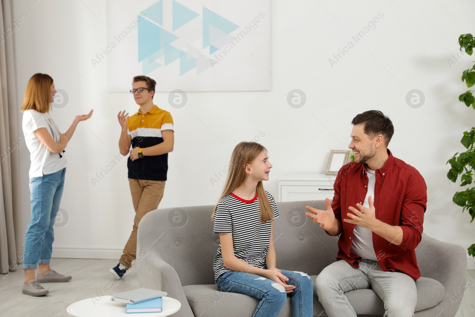 Photo of Happy parents talking with their teenager children at home