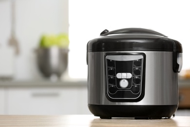 Photo of Modern electric multi cooker on table in kitchen. Space for text