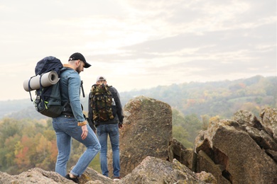 Photo of Hikers with backpacks climbing up mountain on autumn day