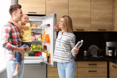 Happy family with bottle of water near refrigerator in kitchen