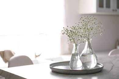 Photo of Vases with gypsophila flowers on table in kitchen, space for text. Interior design