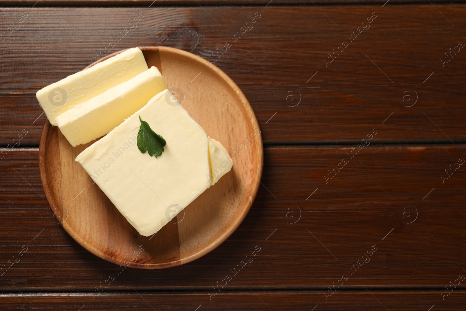 Photo of Cut tasty butter on wooden table, top view. Space for text