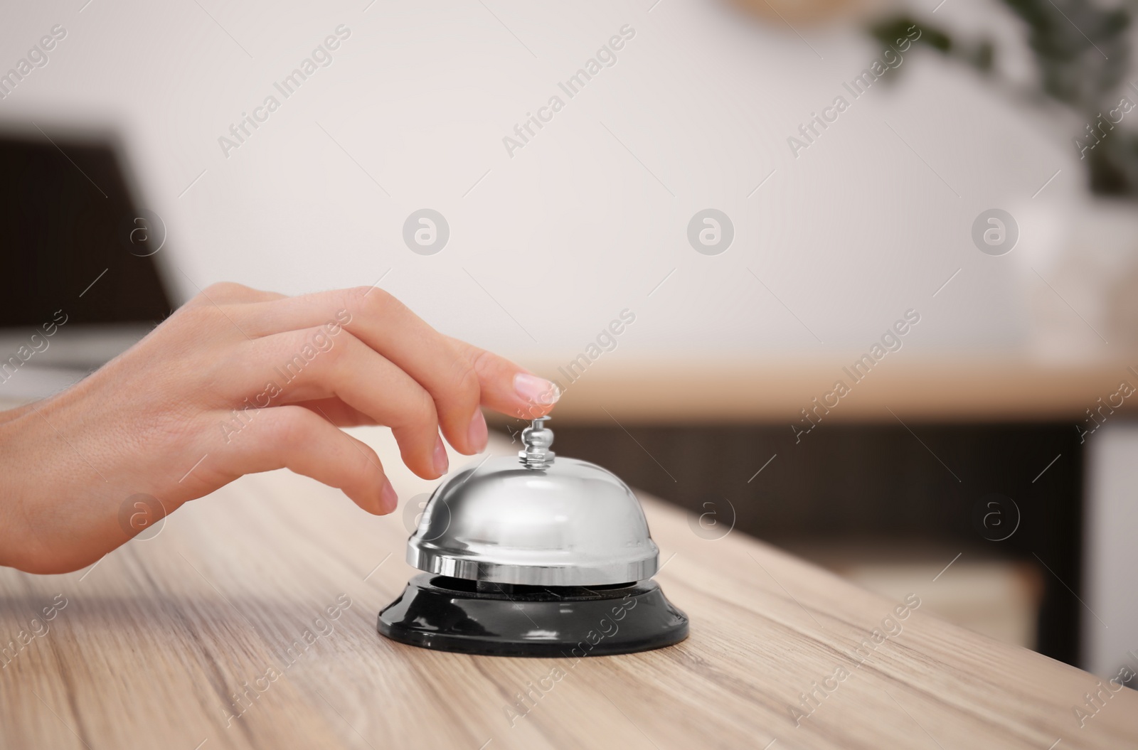 Photo of Woman ringing service bell on reception desk in hotel, closeup