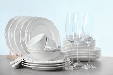 Photo of Set of clean dishes on table against light background