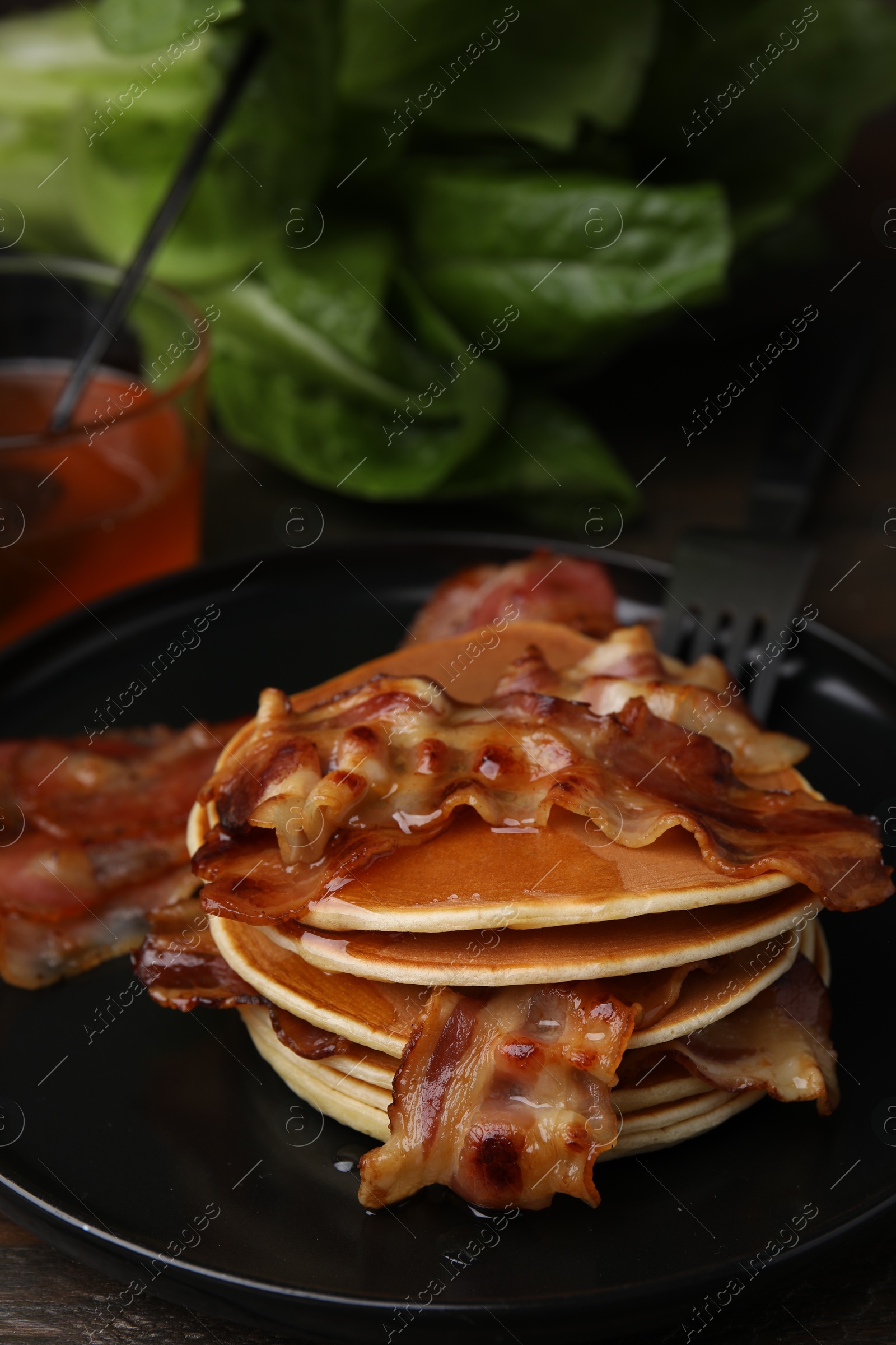 Photo of Delicious pancakes with fried bacon served on wooden table, closeup