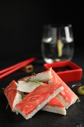 Photo of Fresh crab sticks with sauce served on black table, closeup. Space for text