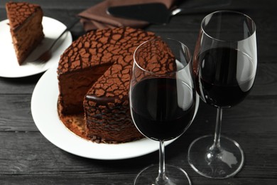 Delicious chocolate truffle cake and red wine on black wooden table