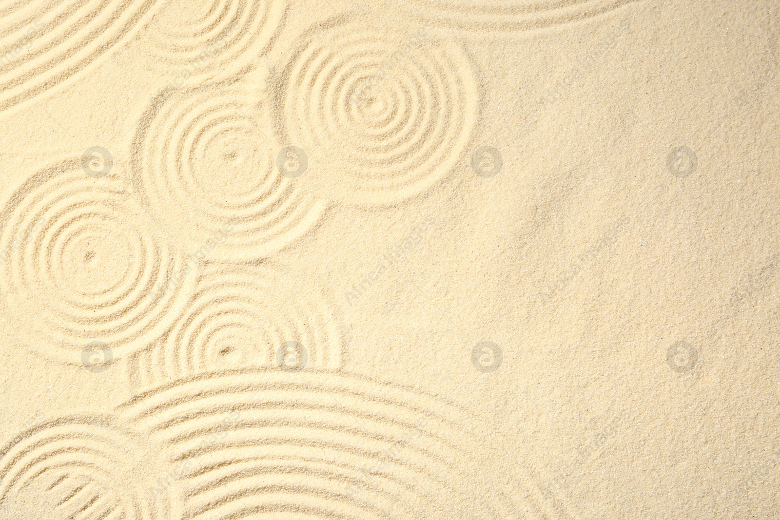 Photo of Zen rock garden. Circle patterns on beige sand, top view