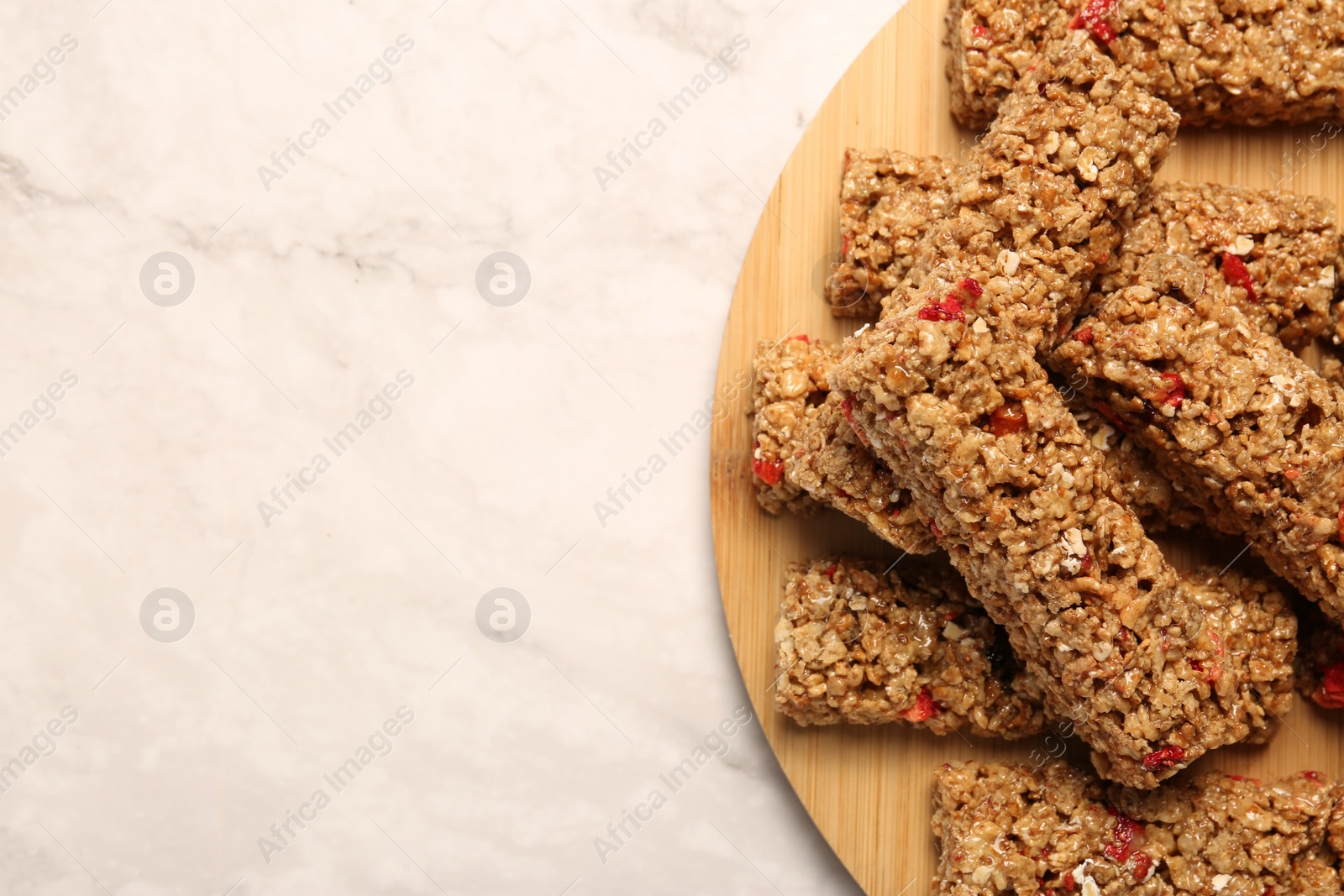 Photo of Tasty granola bars on white marble table, top view. Space for text