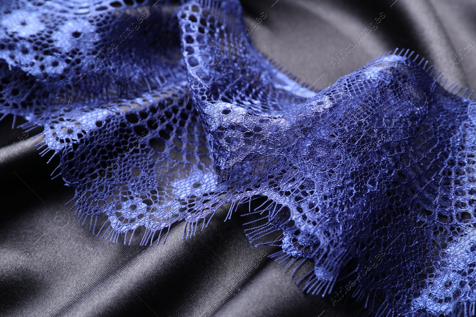 Photo of Beautiful blue lace on black fabric, closeup