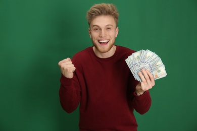 Young man with money on color background