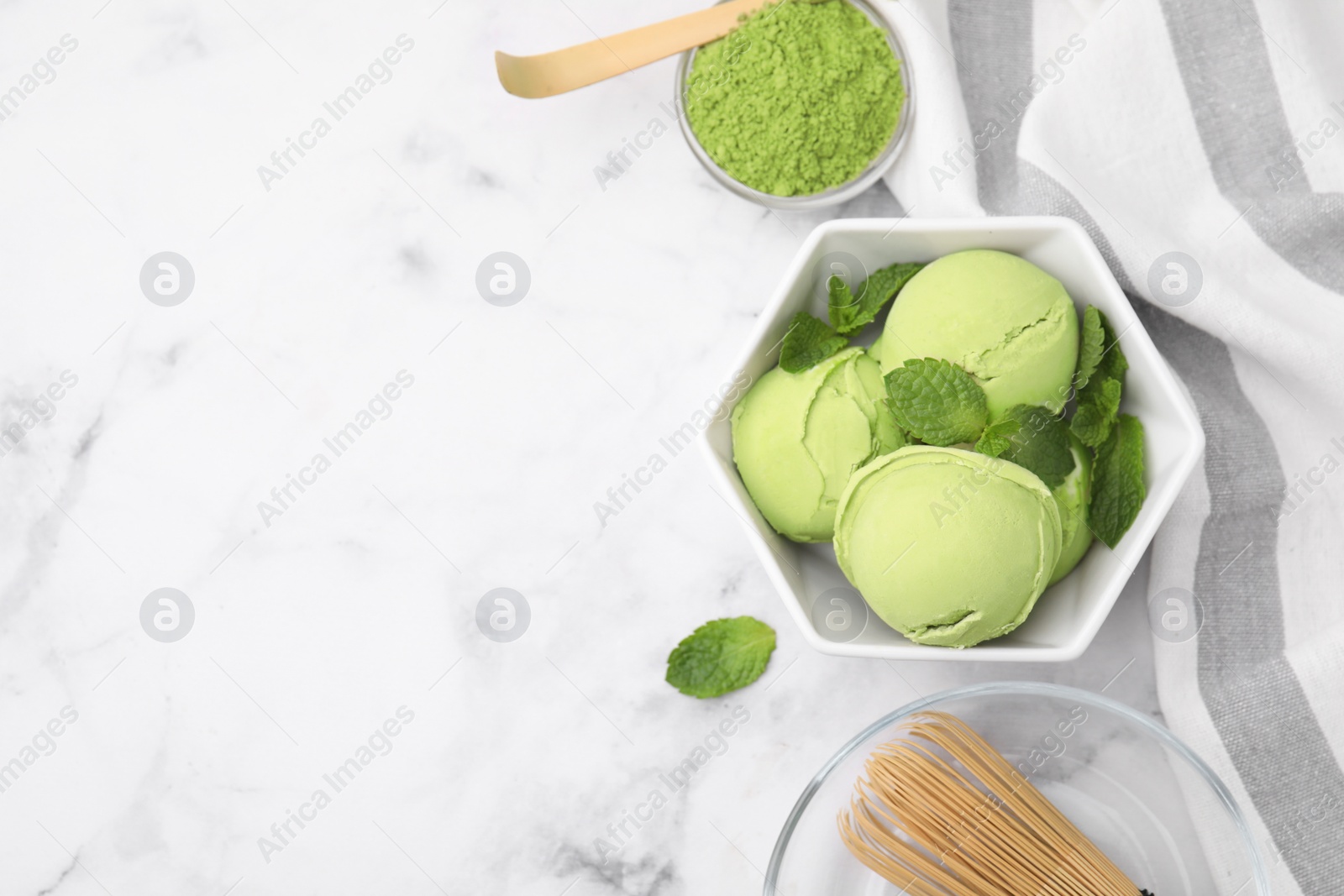 Photo of Tasty matcha ice cream, powder, bamboo whisk and spoon on white marble table, flat lay. Space for text