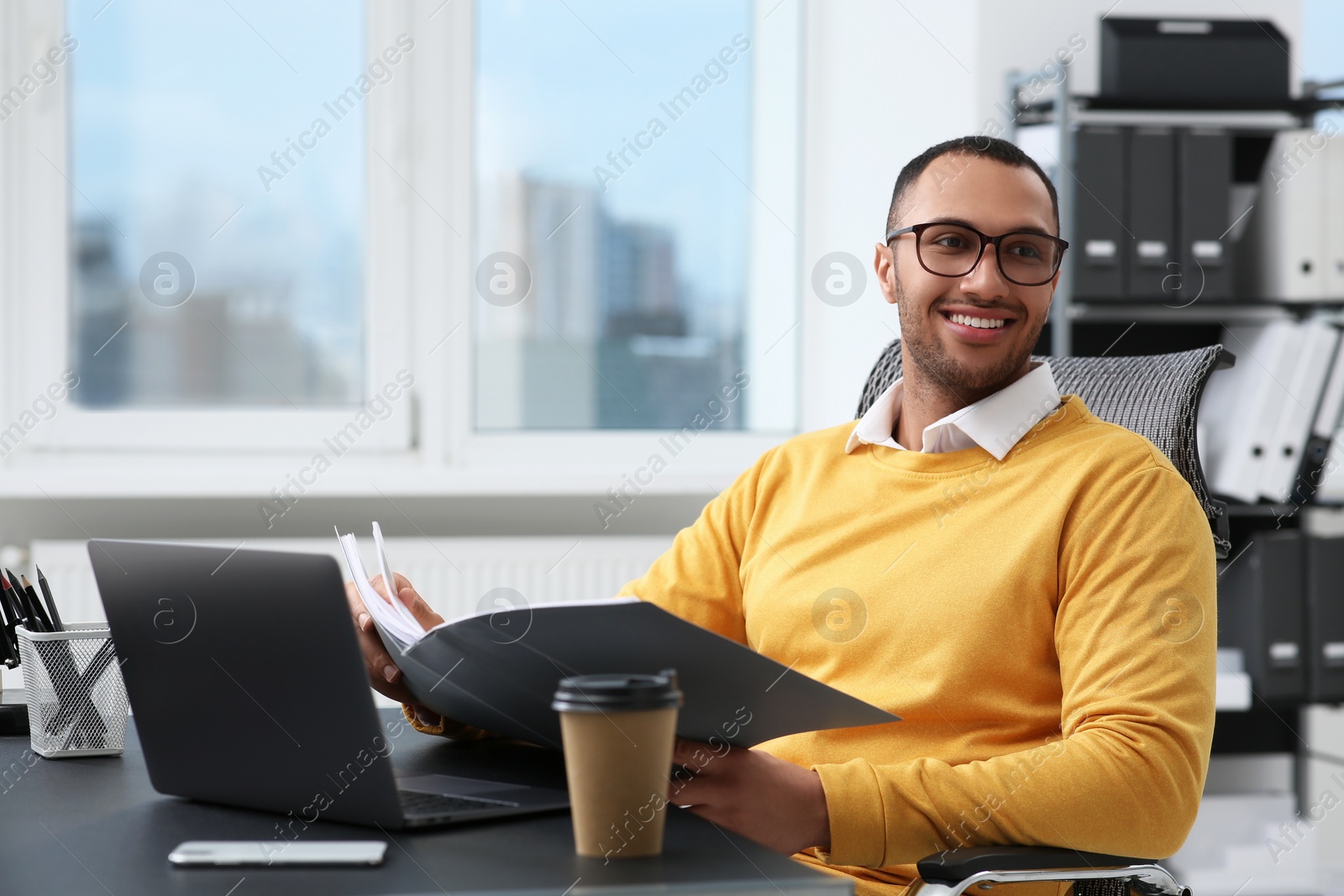 Photo of Young man working with documents at table in office