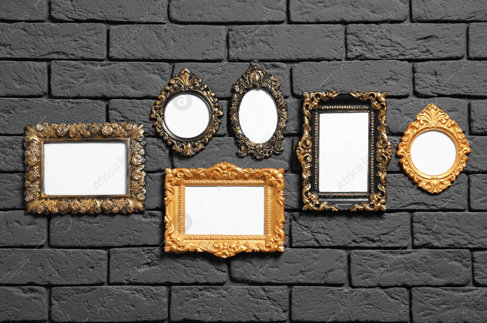 Photo of Empty vintage frames hanging on dark brick wall. Mockup for design