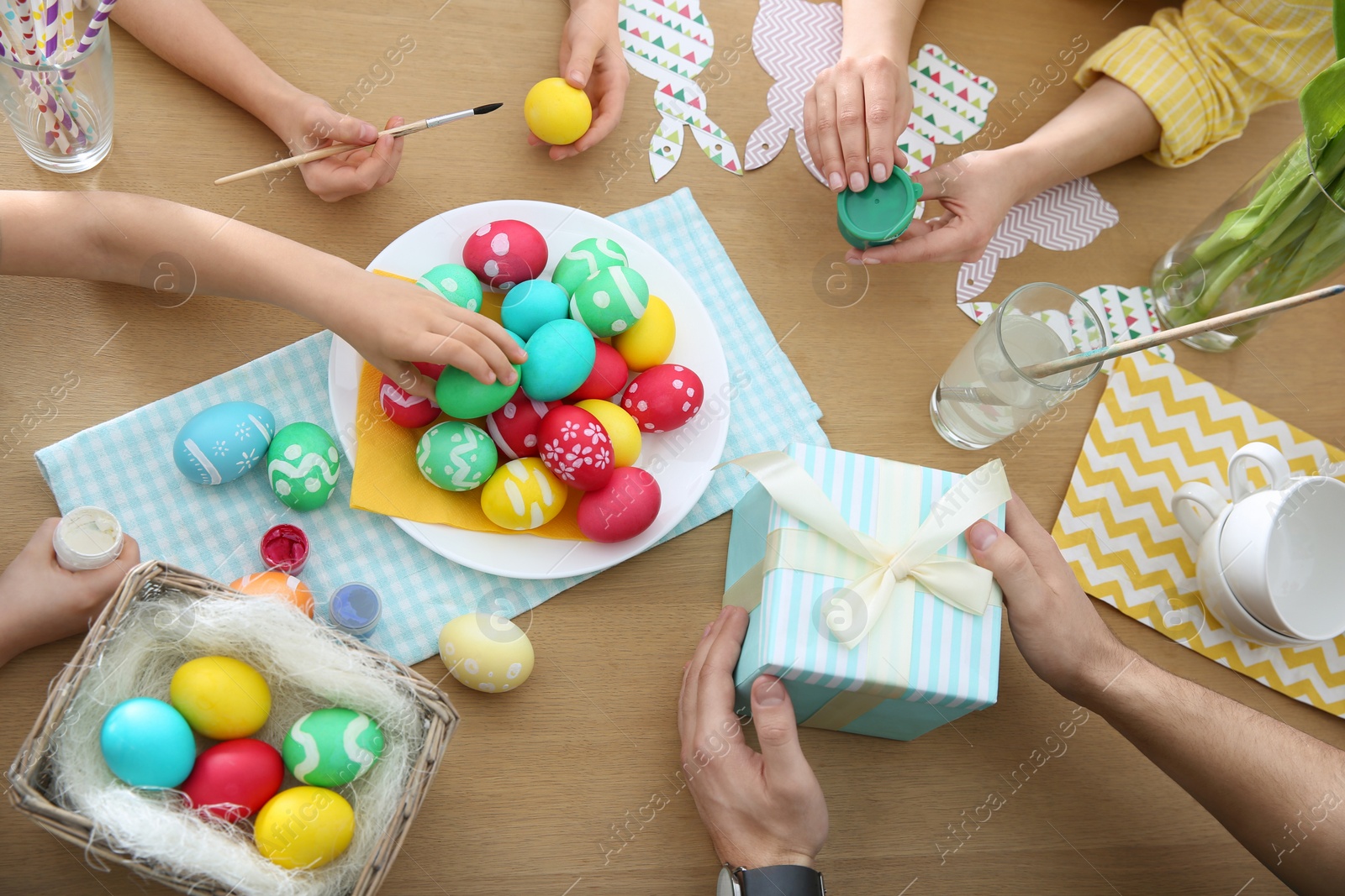 Photo of Family with colorful Easter eggs at table, top view