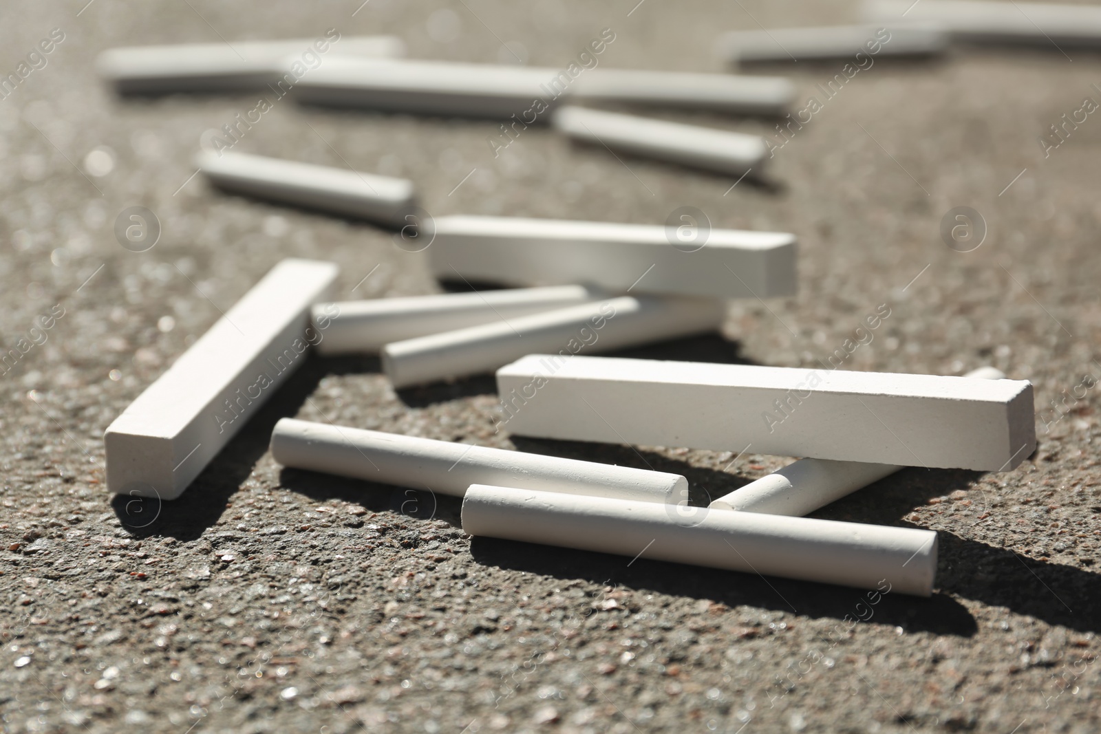 Photo of Many white chalk sticks on asphalt, closeup