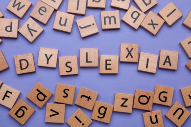 Wooden cubes with word Dyslexia on violet background, flat lay