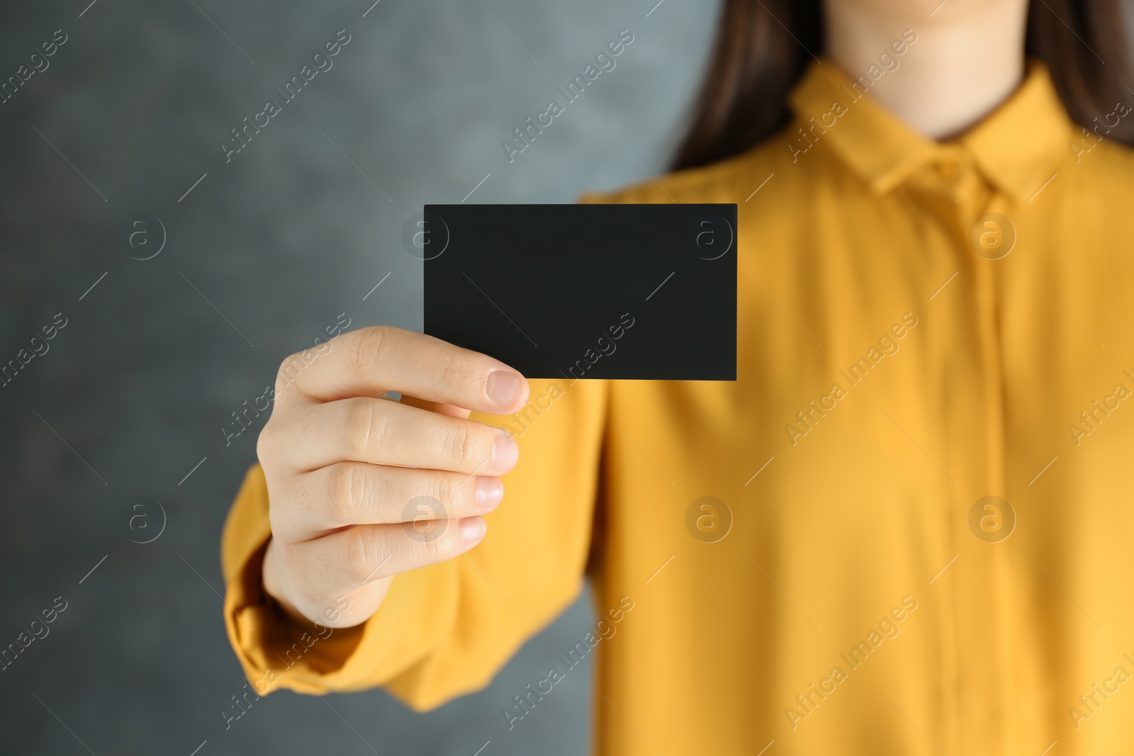 Photo of Woman holding blank business card on grey background, closeup. Mockup for design