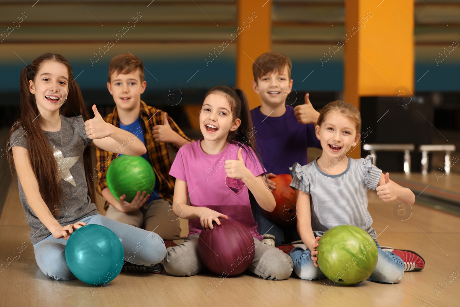 Photo of Happy children with balls in bowling club