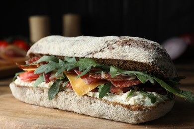 Delicious sandwich with fresh vegetables and prosciutto on wooden table, closeup