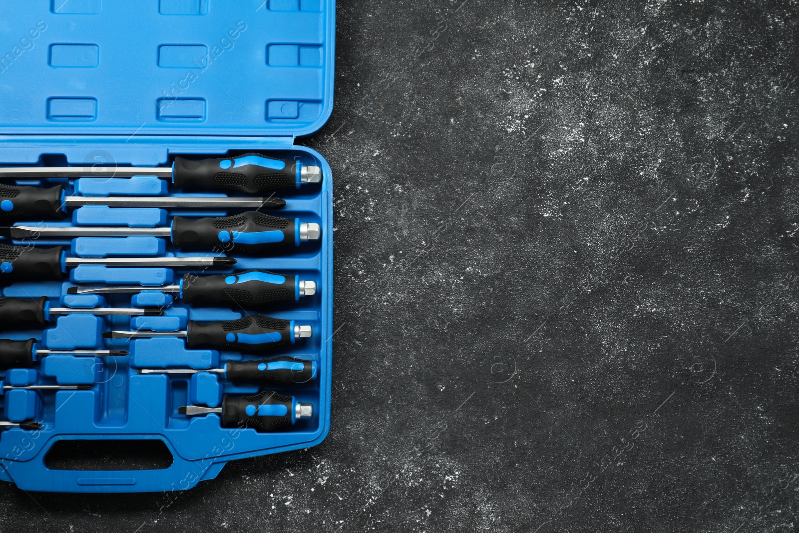 Photo of Set of screwdrivers in open toolbox on dark textured table, top view. Space for text