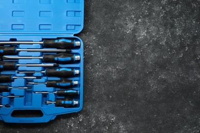 Set of screwdrivers in open toolbox on dark textured table, top view. Space for text