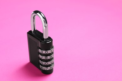 Photo of One steel combination padlock on pink background, closeup. Space for text